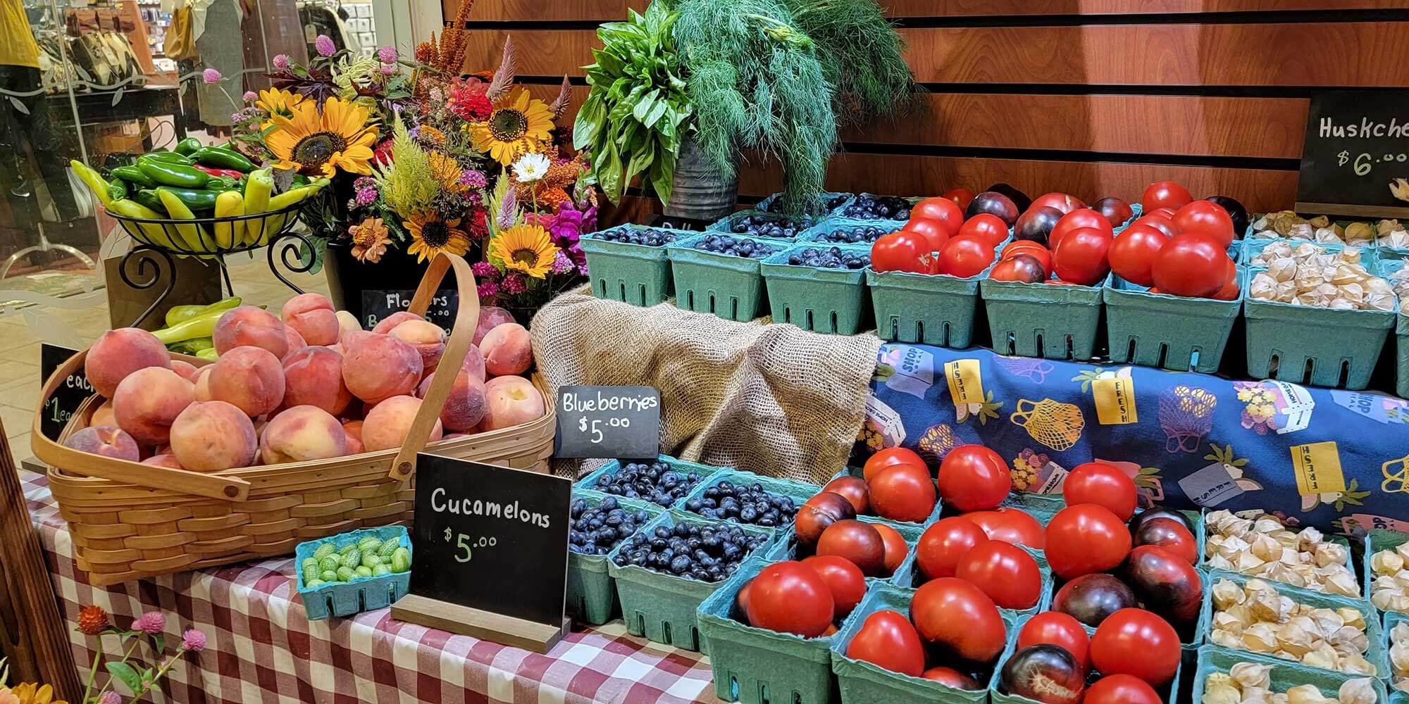 A display table full of fruits and vegetables, including blueberries and peaches
