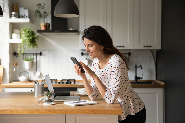 A middle aged woman happily browses her phone for an OB/GYN provider
