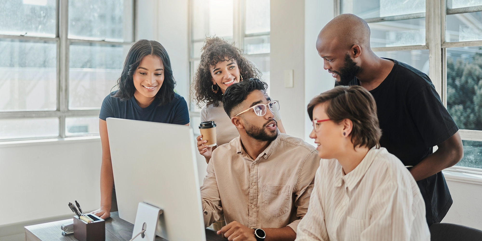 A group of interns from different backgrounds commiserate over a computer monitor