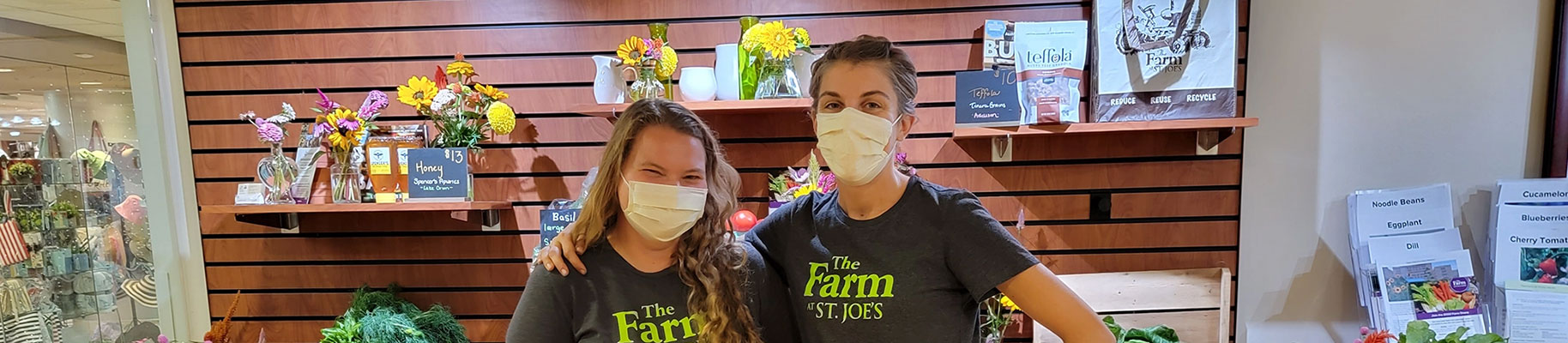 Employees of the Farm pose together with their arms outstretched in front of a vegetable greenhouse