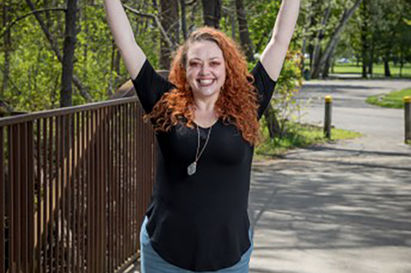 Danielle Jamrog stands with her arms above her head, overjoyed after losing weight from bariatric surgery